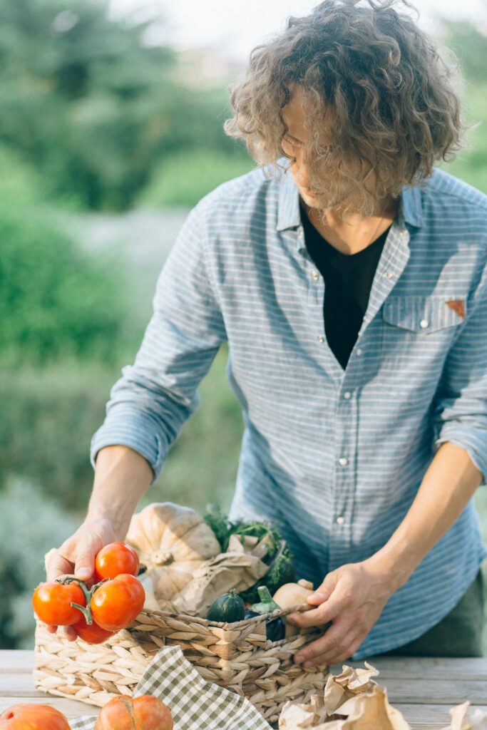 Caucasian man arranging fresh vegetables in woven basket outdoors.